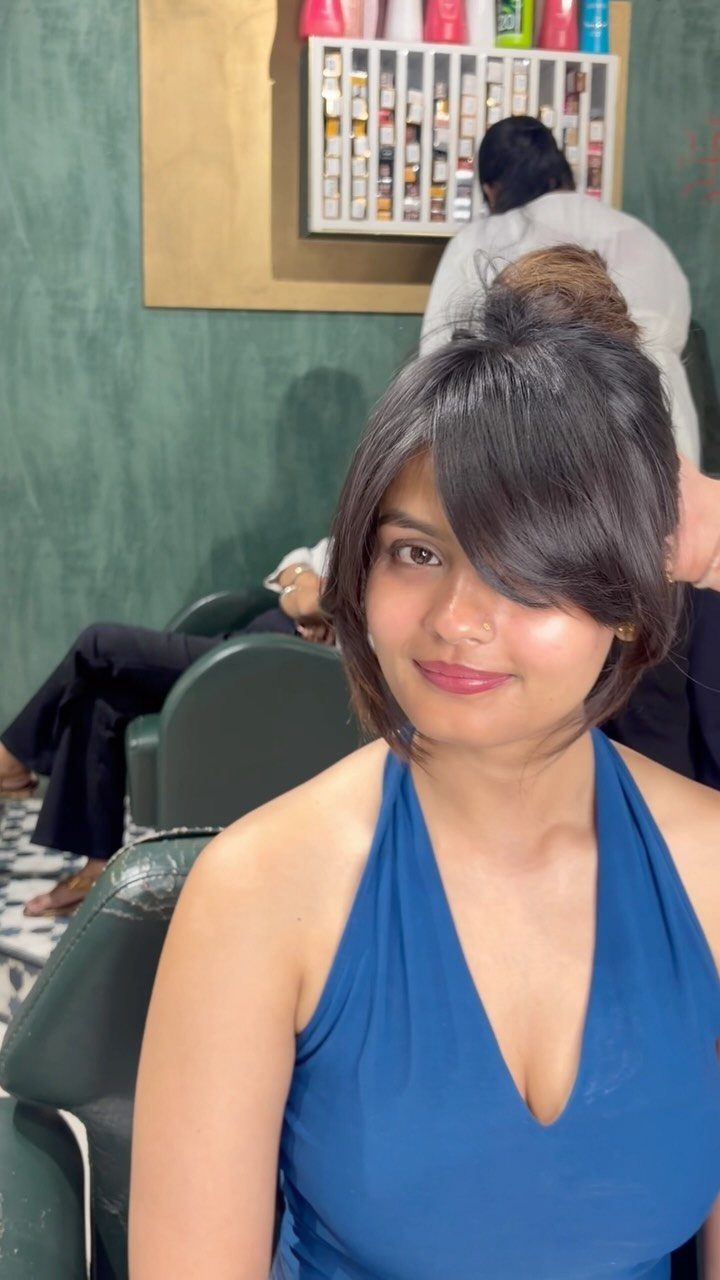 Woman with dark layered hair and side-swept fringe in a salon