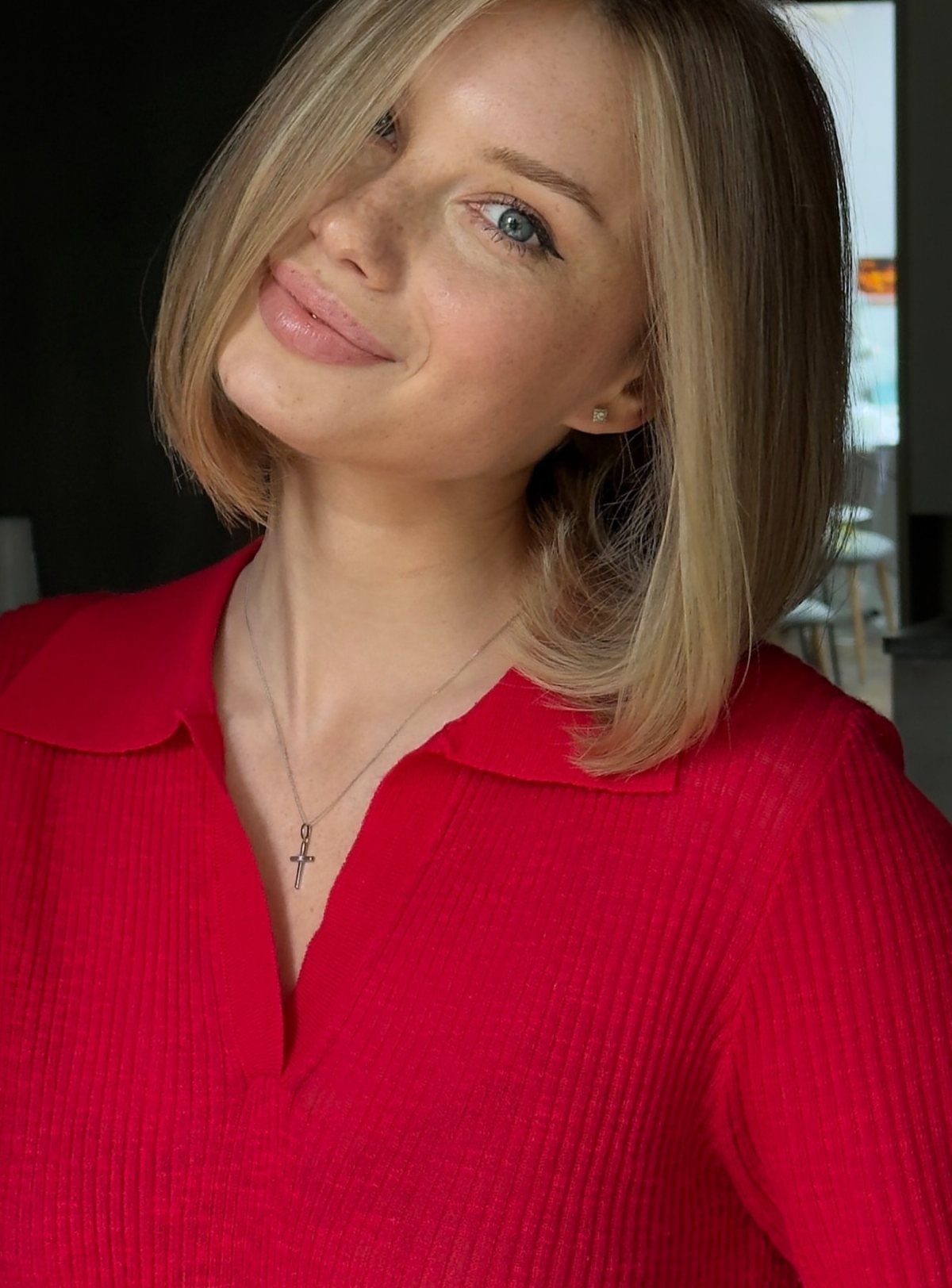 Woman with a smooth blonde bob and side part wearing a red top