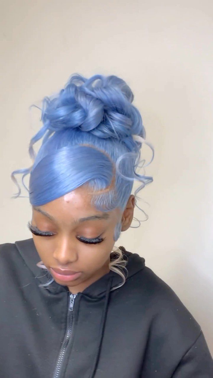 Blue-haired person wearing a fluffy high bun with loose curls