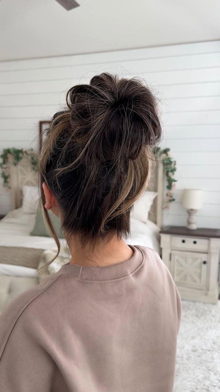 Loose dark brown top-knot with wispy strands on a person seen from behind