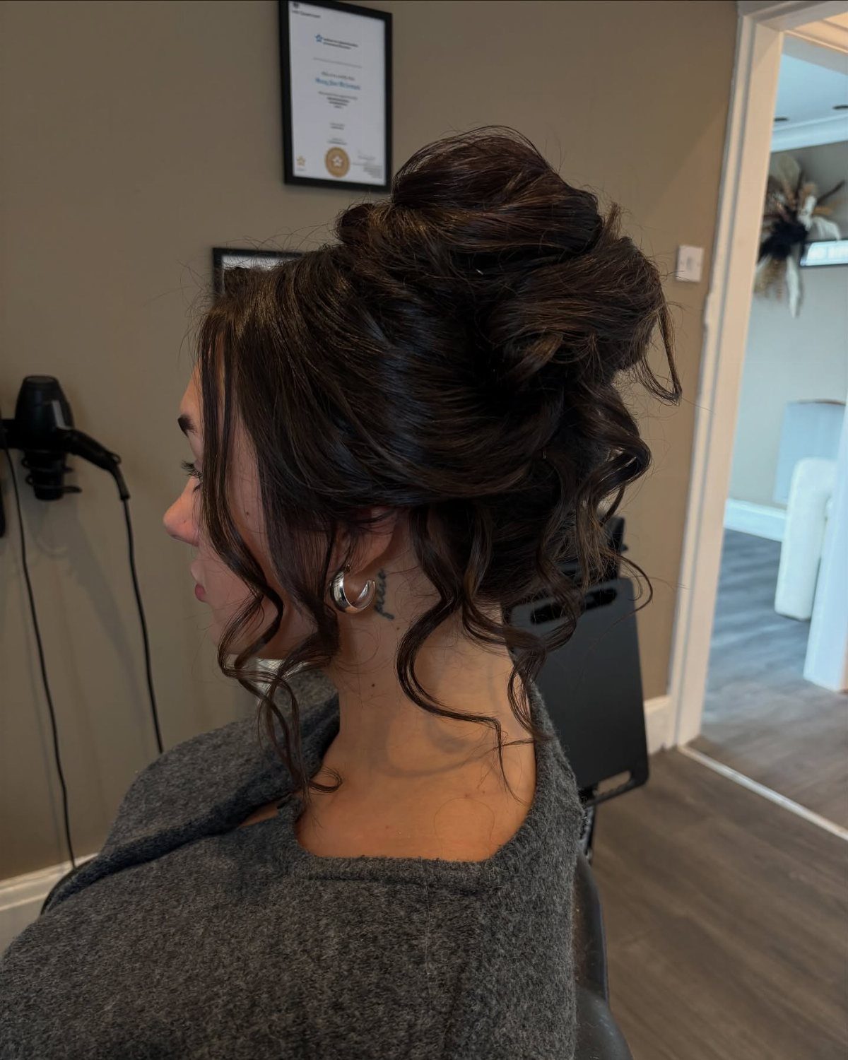 Dark-haired woman wearing a voluminous twisted updo with loose curls