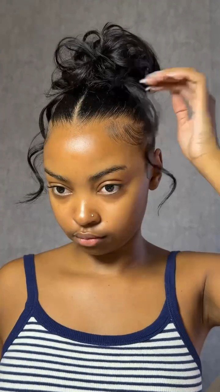 Woman wearing a high messy bun with a smooth hairline and loose curls