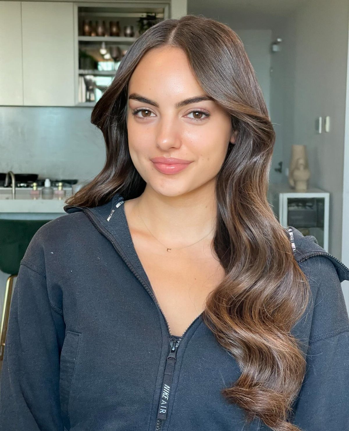 Woman with a middle part and long, loose brown waves over one shoulder