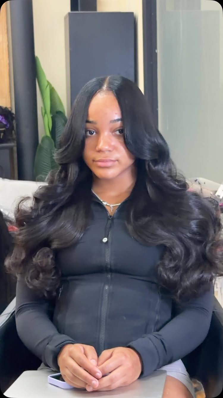 Woman with long, voluminous black curls framing a center part