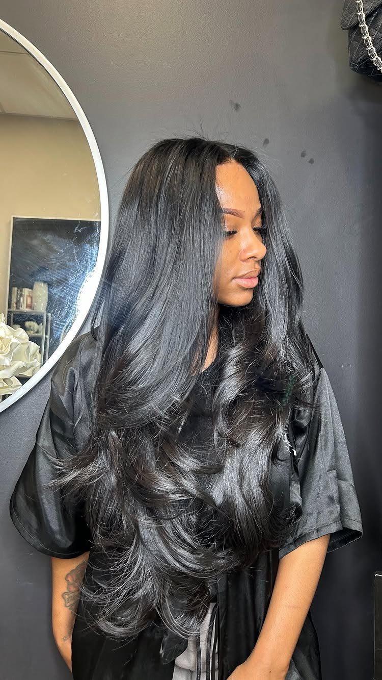 Long black layered hair falls in curled, face-framing sections from a center part