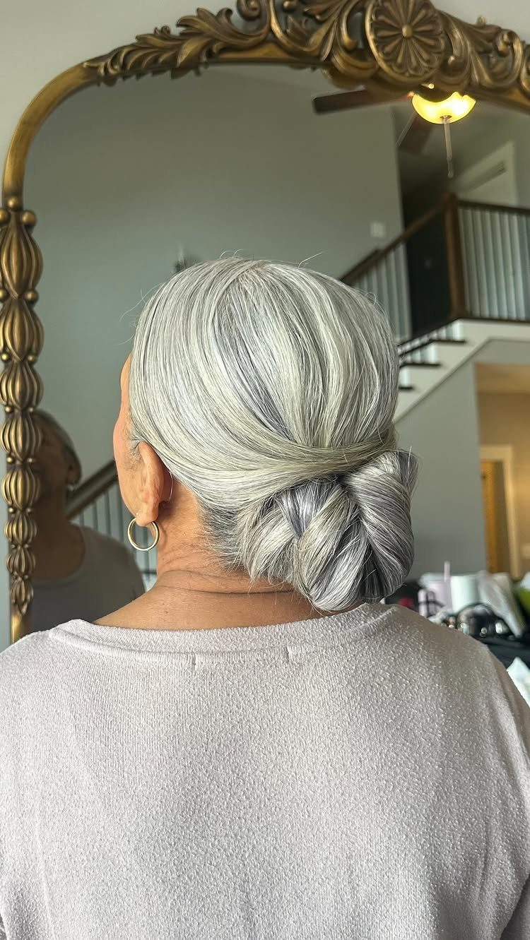 Silver-haired woman shows a smooth low braided bun from behind