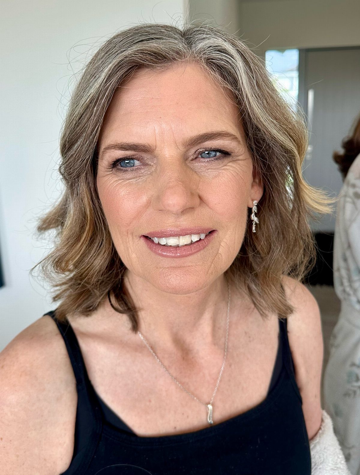 Older woman smiling with casually brushed shoulder-length waves and a center part