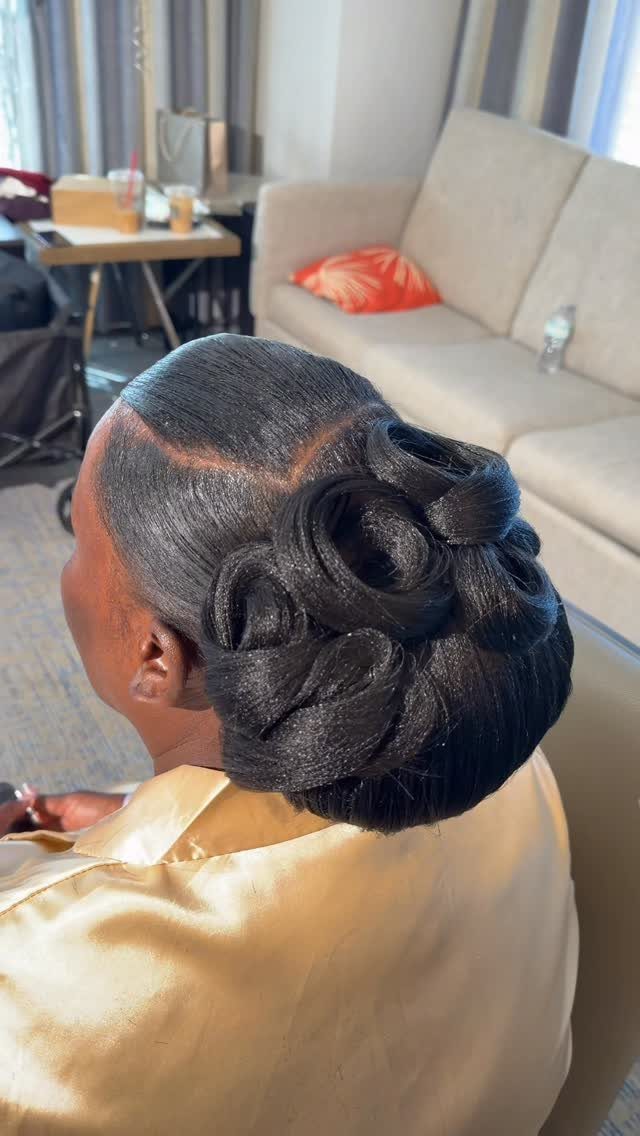 Dark hair styled into a smooth curled updo with pinned loops
