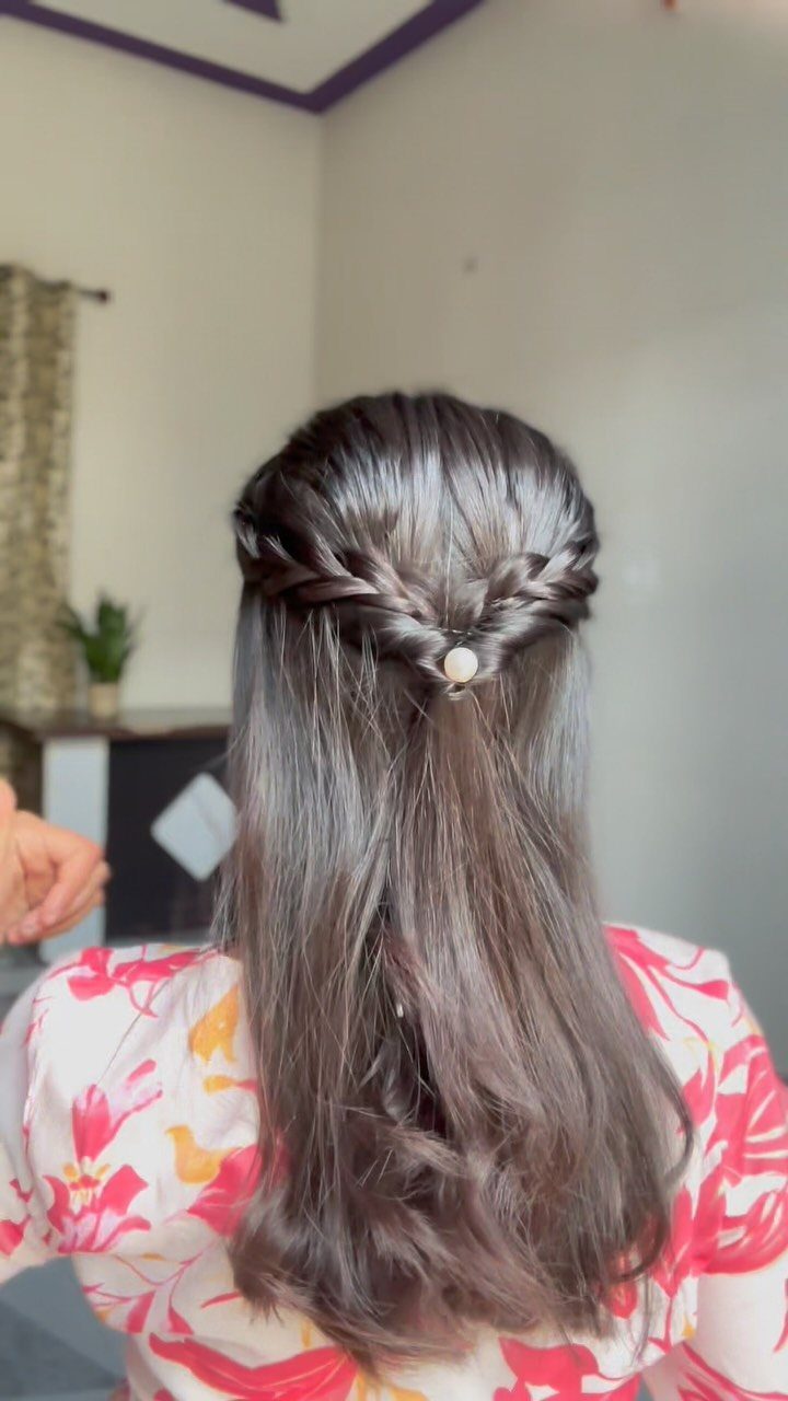 Long brown hair styled half-up with twisted sections pinned by a small clip