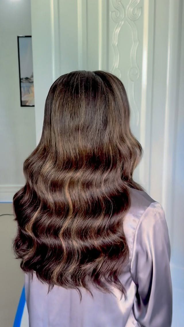 Long dark brown hair styled in glossy, defined Hollywood waves