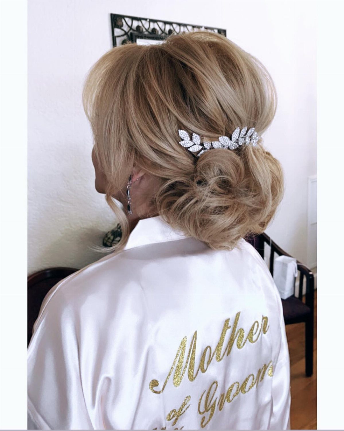 Loose blonde curls pinned into a low updo with a silver hairpiece