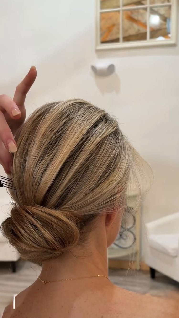 Blonde hair swept into a smooth low bun at the nape
