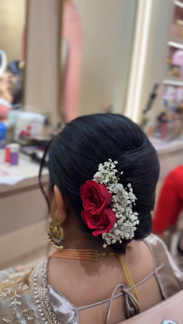 Low black updo decorated with a red rose and small white flowers