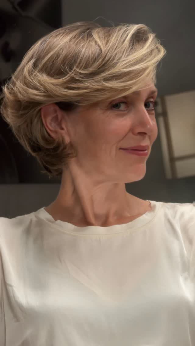 Woman with a voluminous short blonde hairstyle and a swept side part