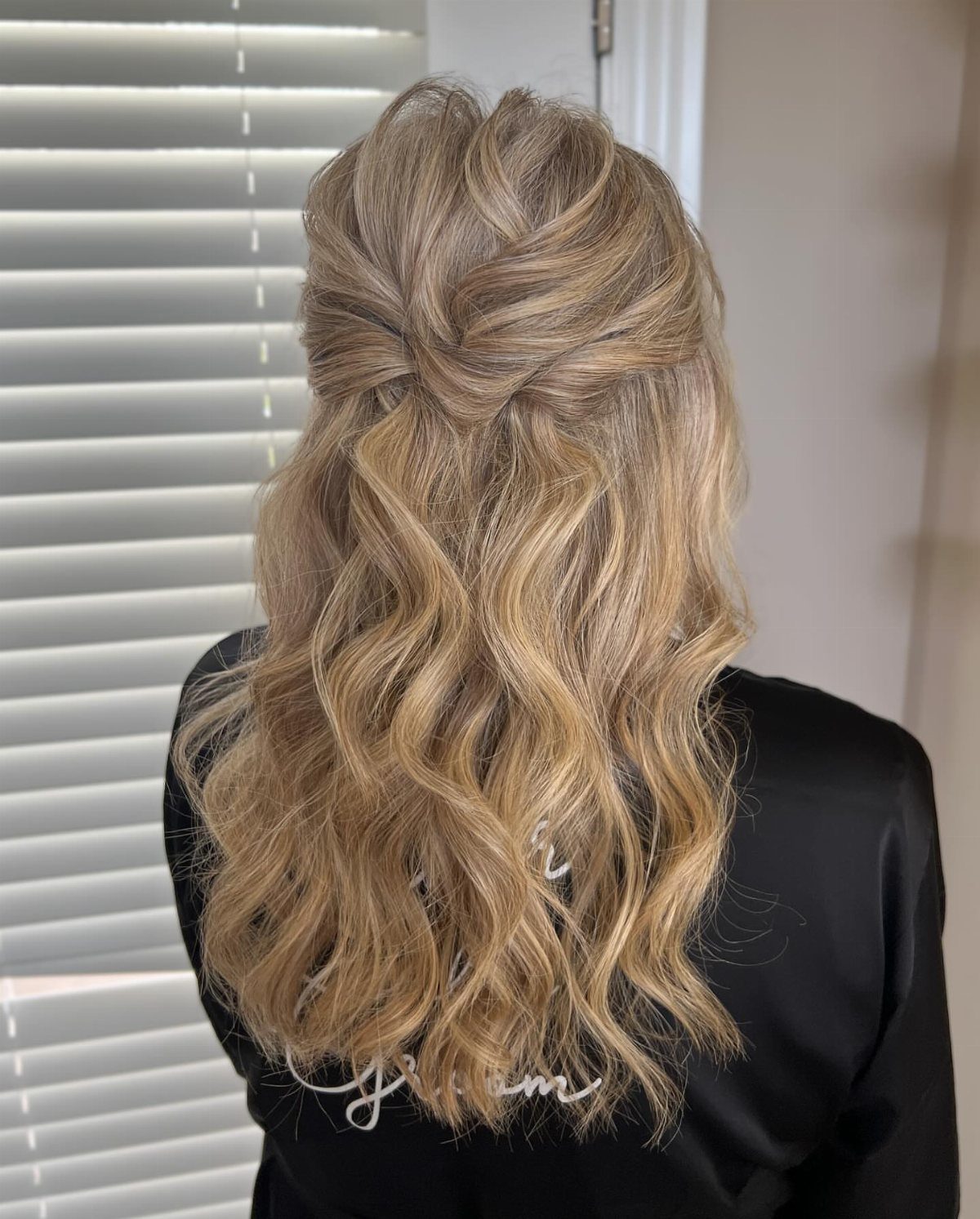Blonde twisted half-up hairstyle with long loose waves cascading down