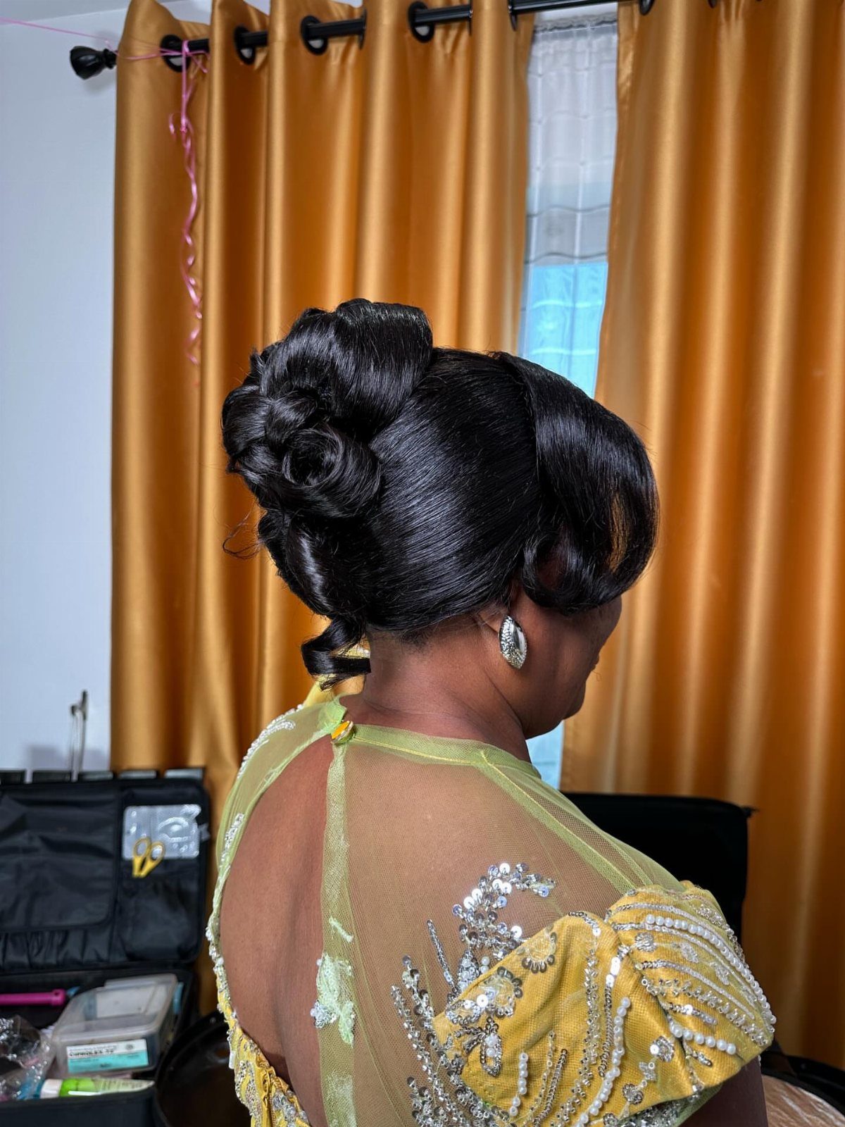 Voluminous black chignon with sculpted sections above a yellow embellished outfit