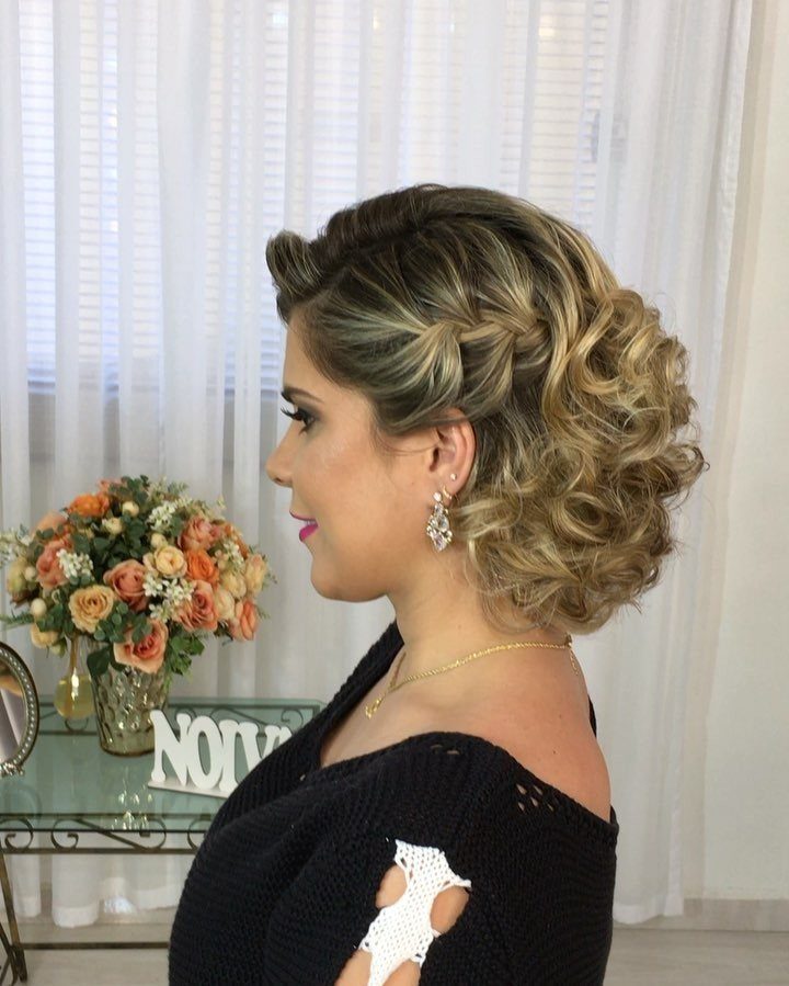 Woman with an elaborate curled blonde updo, earrings, and a black top