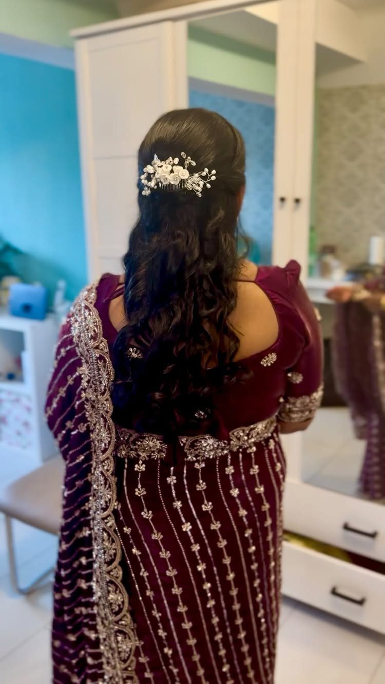 Woman with long wavy hair and white floral hairpiece in an embroidered burgundy outfit