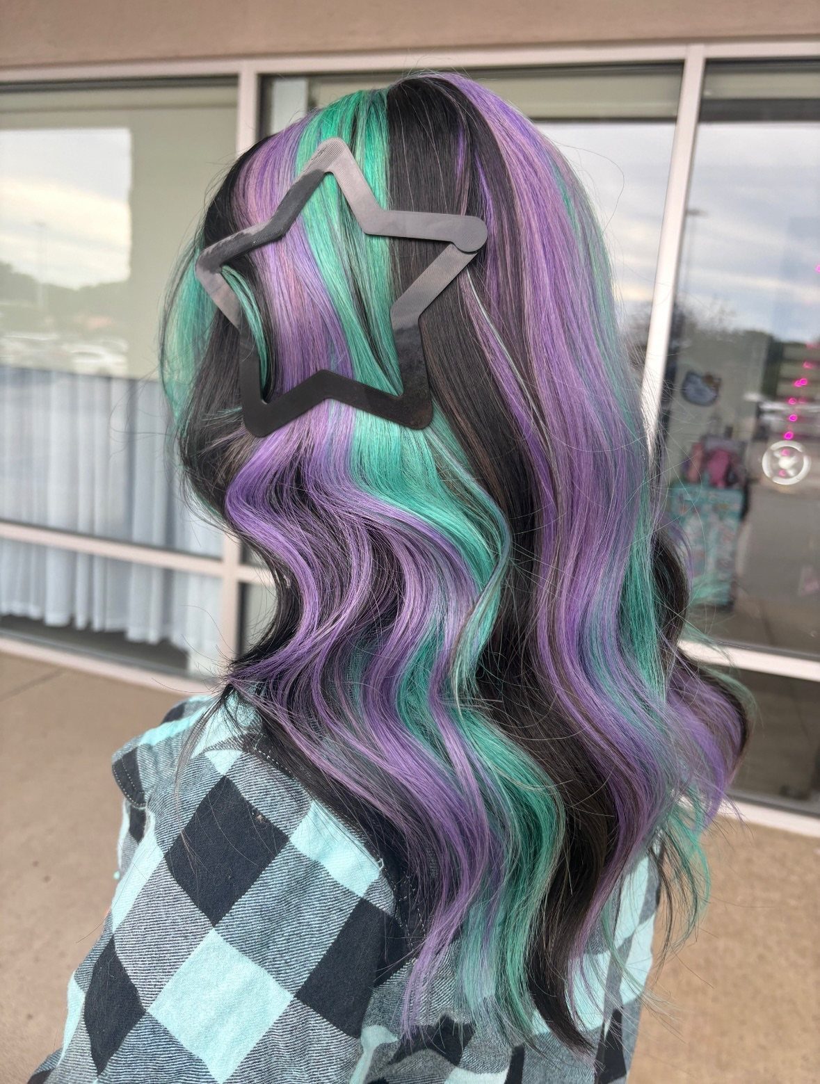 Wavy black hair with blended teal, green, and purple highlights and star clip