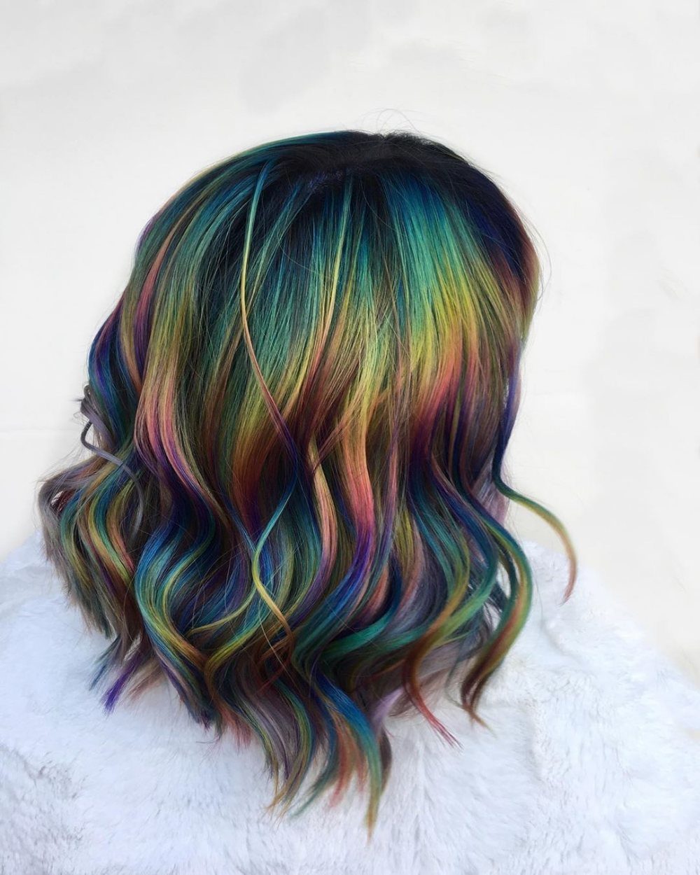 Wavy dark hair with blended teal, blue, purple, pink, and gold streaks