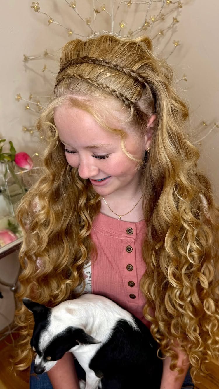 Blonde woman with long curls and a braided headband holds a black-and-white dog