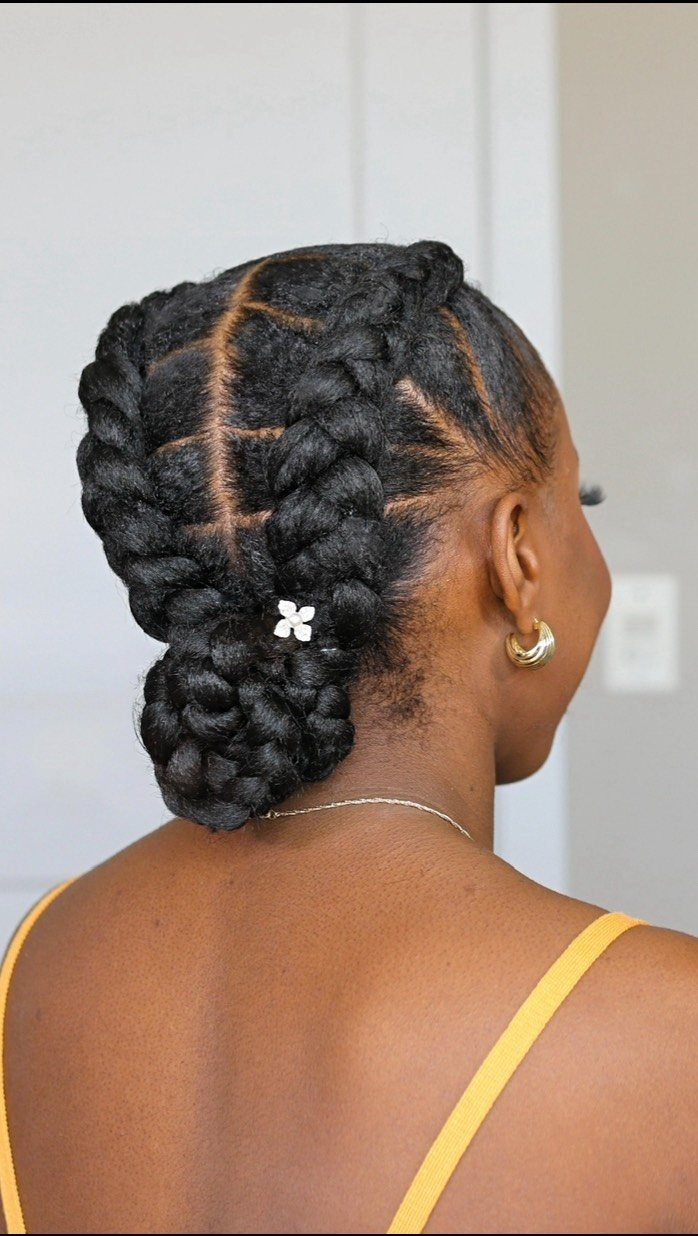 Thick braids gathered into a low bun with a small white hair clip