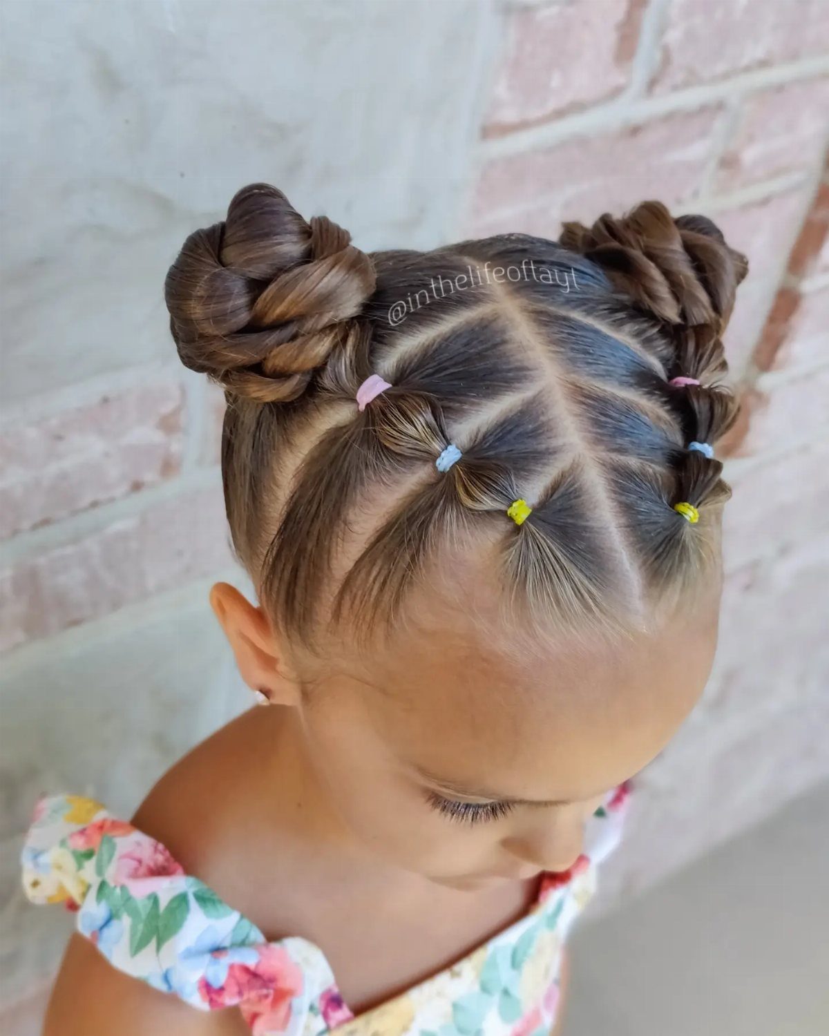 Girl with two bubble-braid ponytails wrapped into small high buns