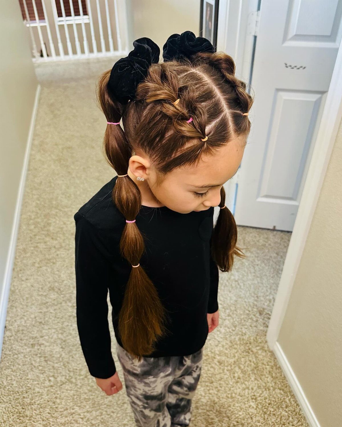 Child wearing two bubble braids gathered into low pigtails with pink elastics