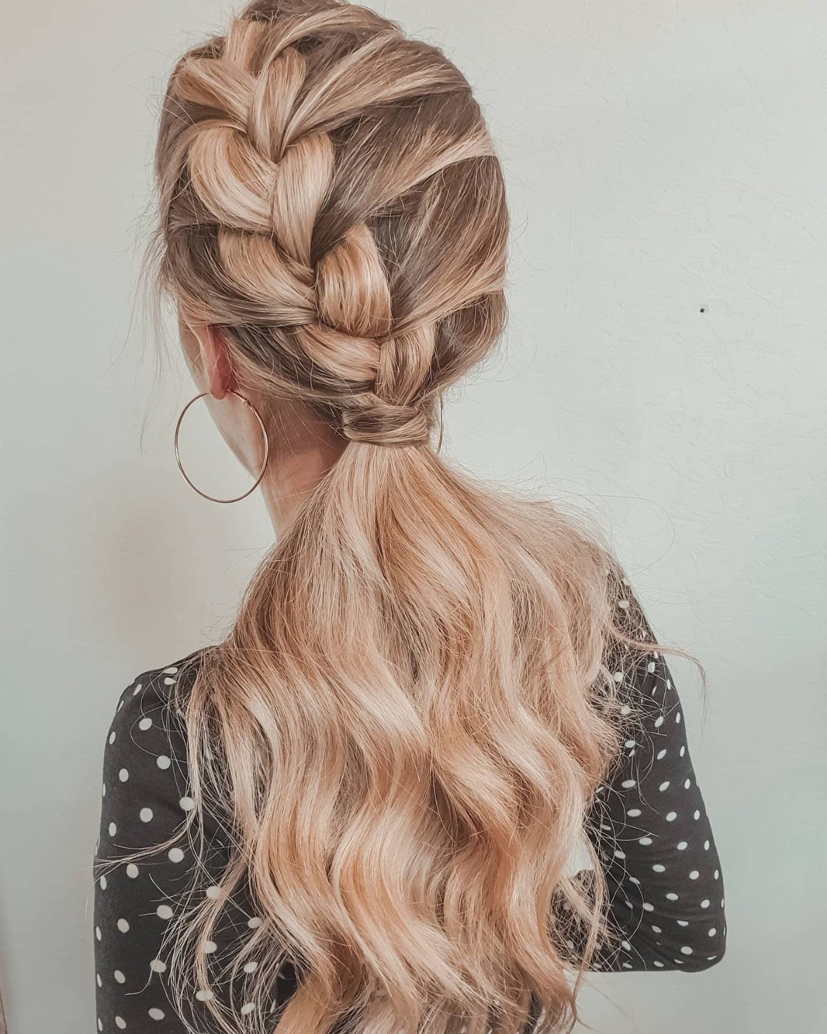Blonde crown French braid flowing into a long wavy ponytail