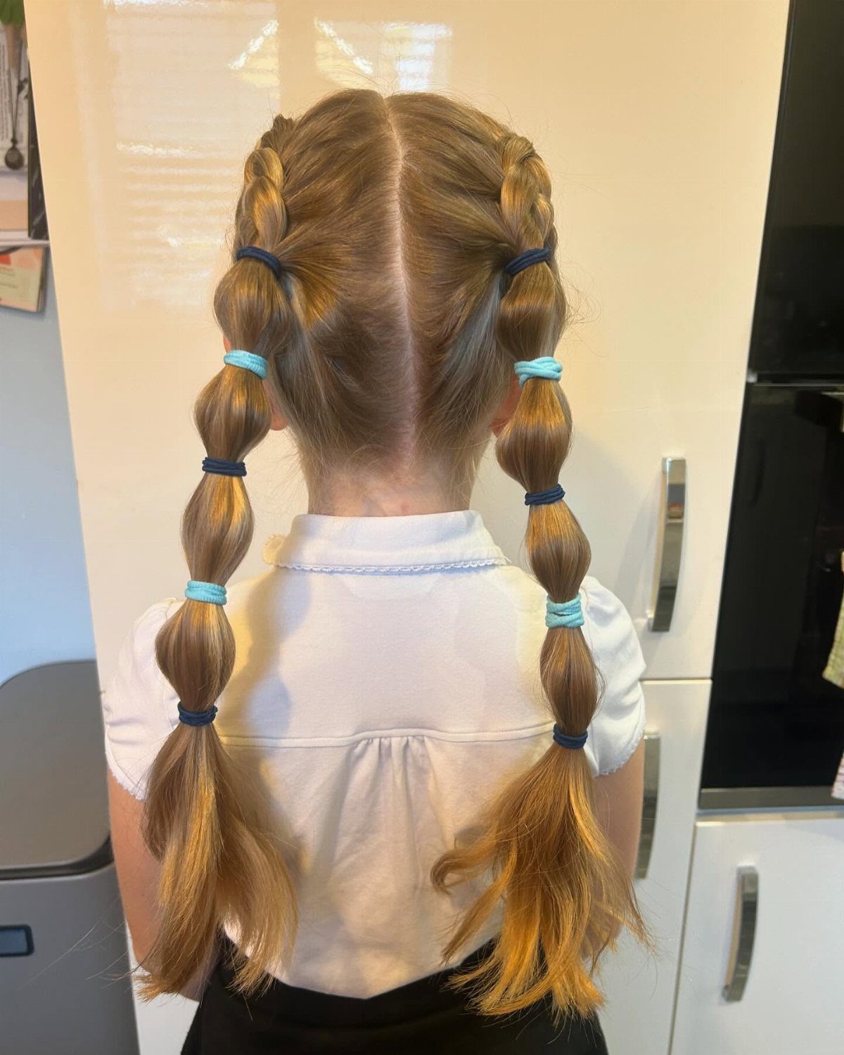 Dutch-braided pigtails with blue elastics and bubble sections down the hair