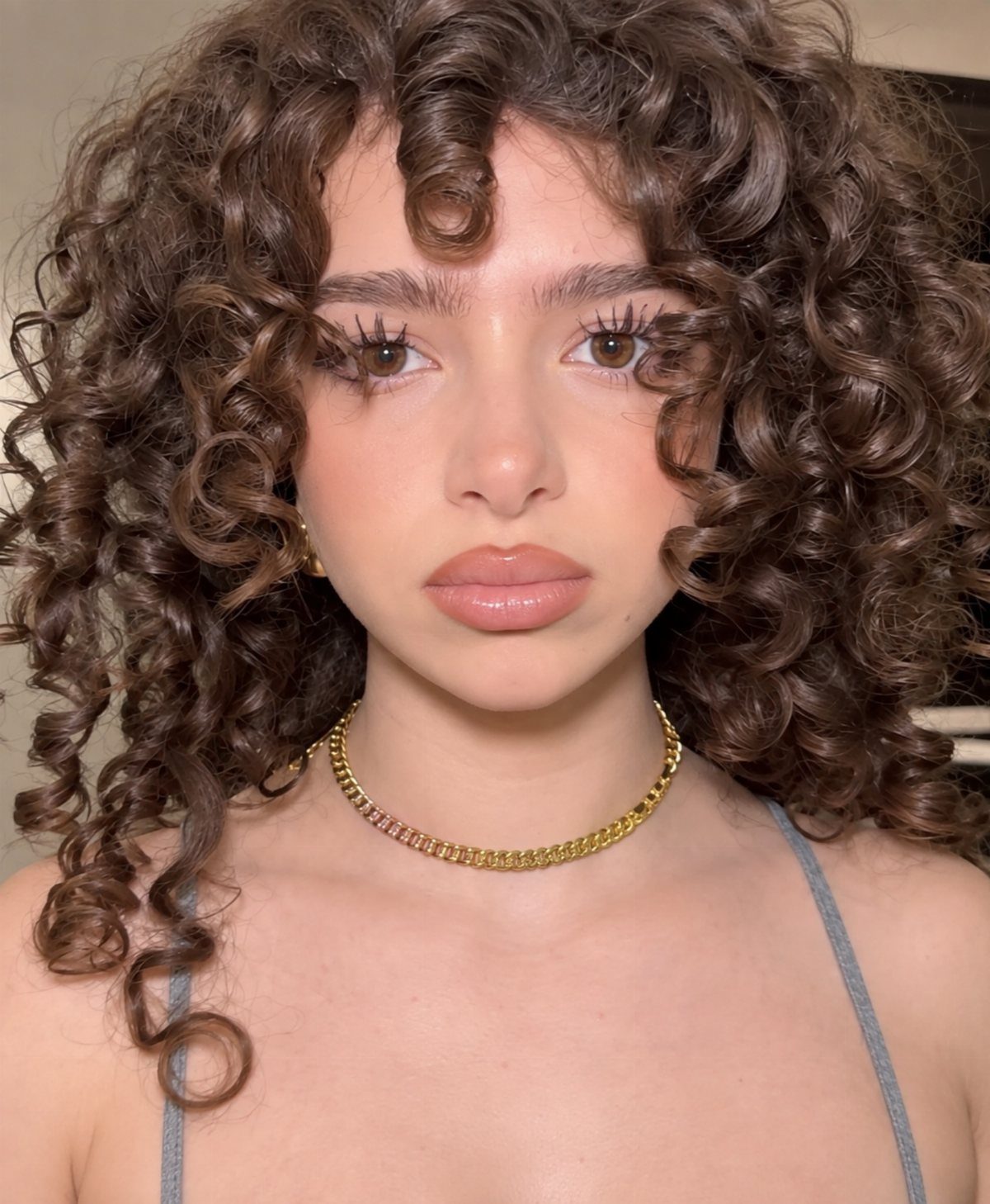 Young woman showing voluminous brown curls framing her face and shoulders
