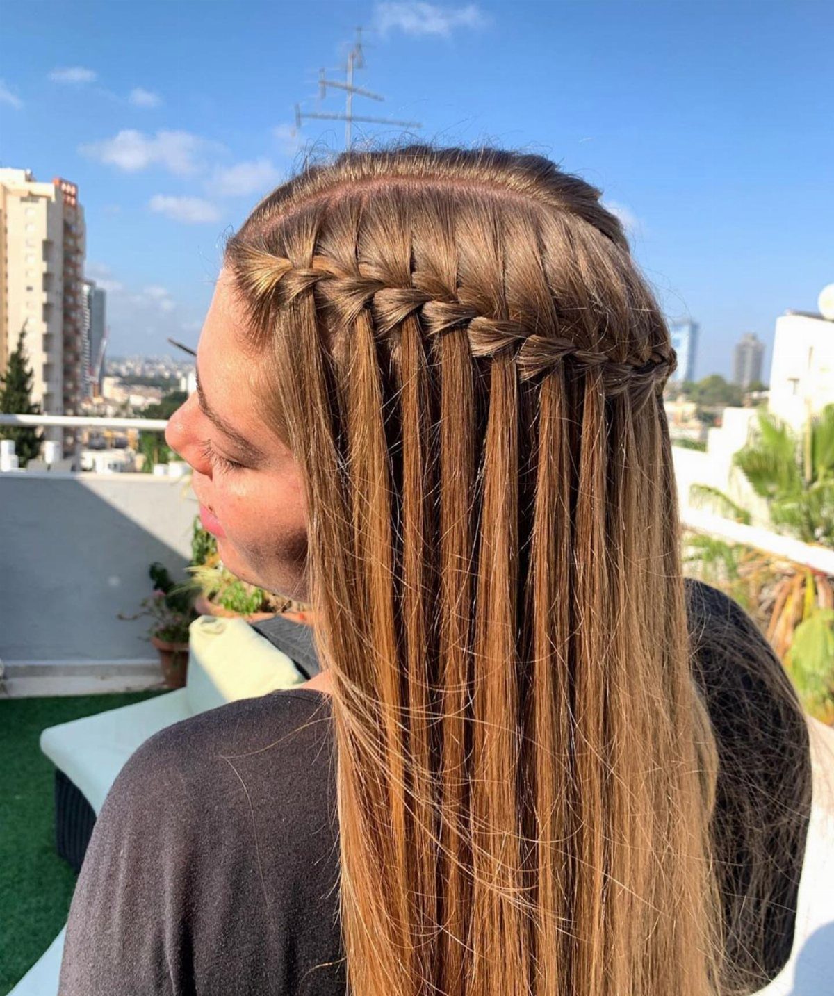 Woman with long brown hair wearing a thick waterfall braid outdoors