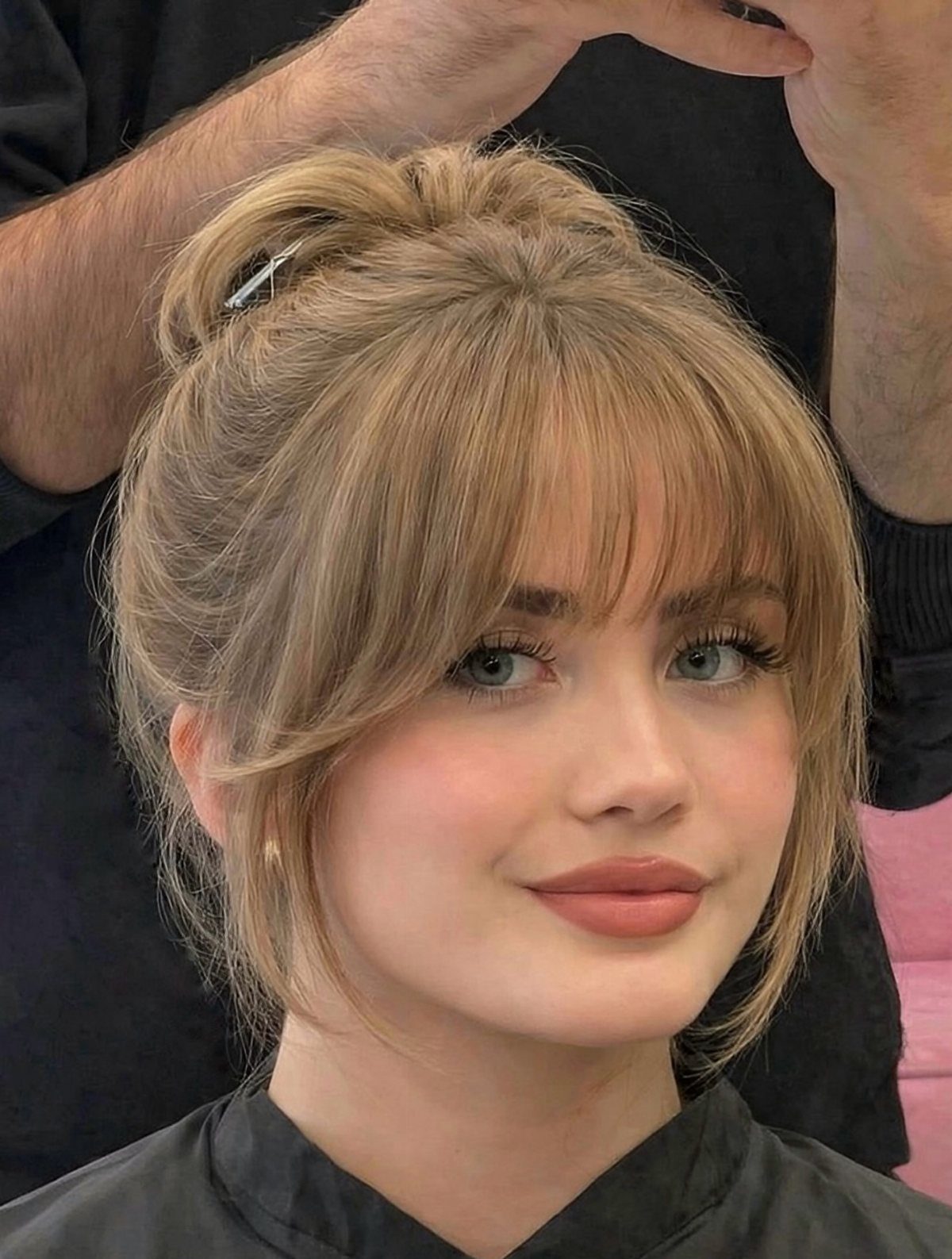 Blonde woman with wispy eyebrow-grazing bangs in a salon