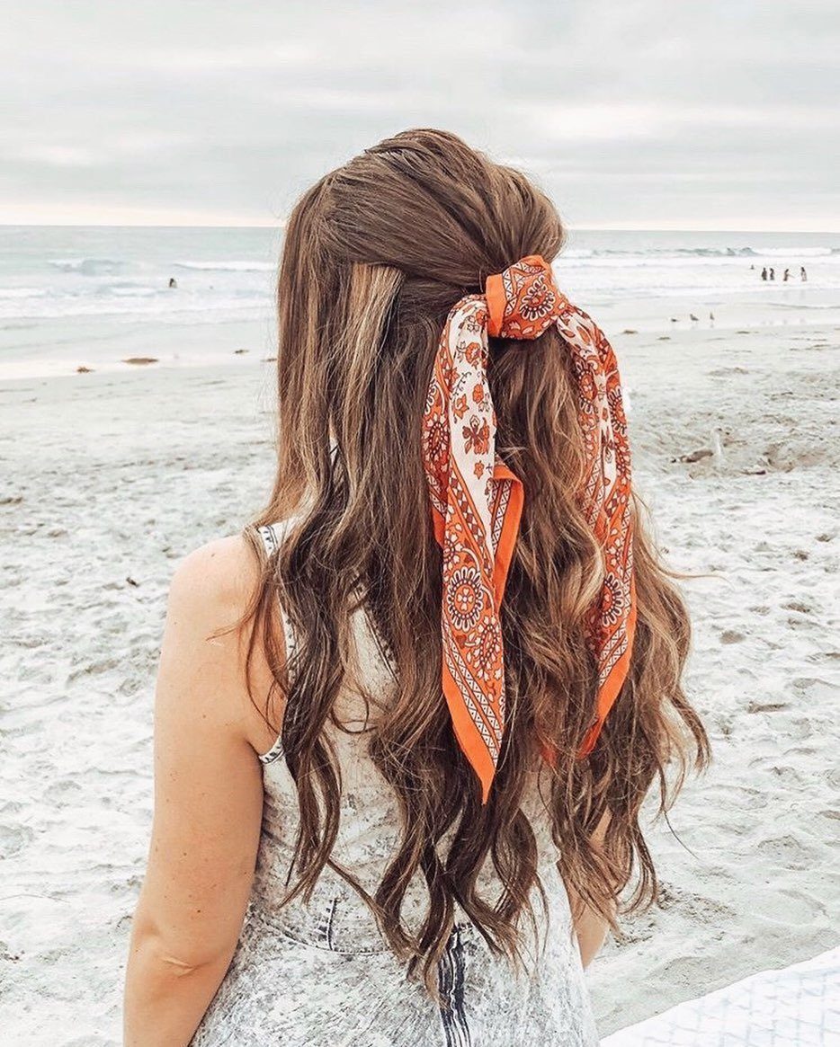 Long, loose brown beach waves tied back with an orange patterned scarf