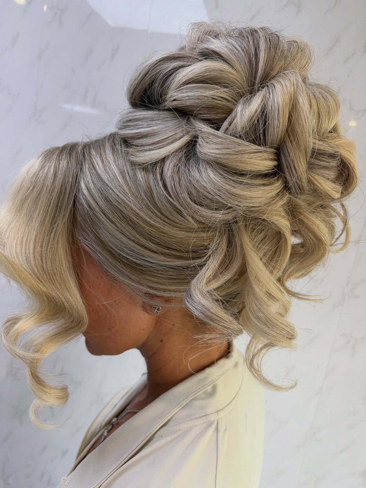 Blonde braided updo with voluminous twists and loose curls on a woman