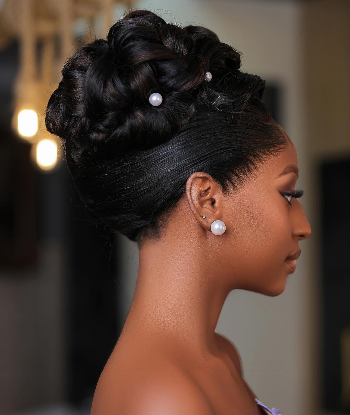 Elaborate dark braided updo decorated with pearl pins on a woman in profile