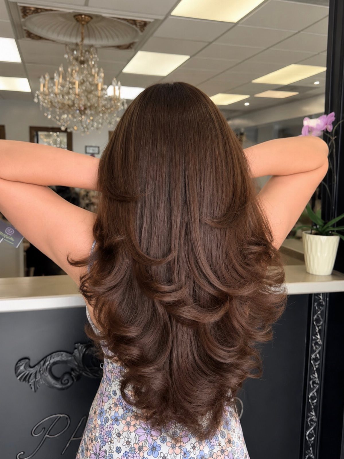 Long brown hair styled in cascading, voluminous layers at a salon