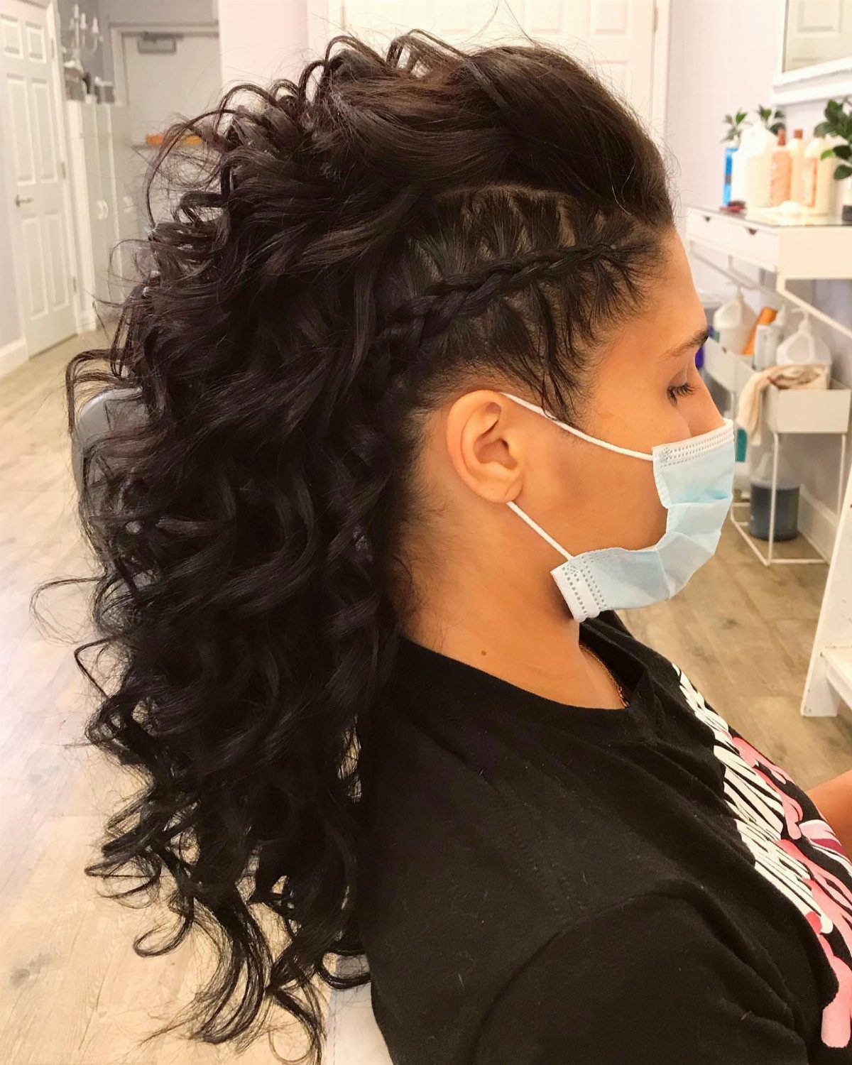 Curly mohawk updo with closely shaved sides, a braid, and cascading dark curls