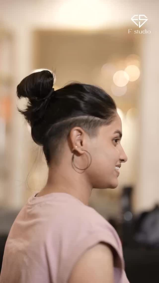 Woman with a sleek high bun and shaved sides, viewed in profile