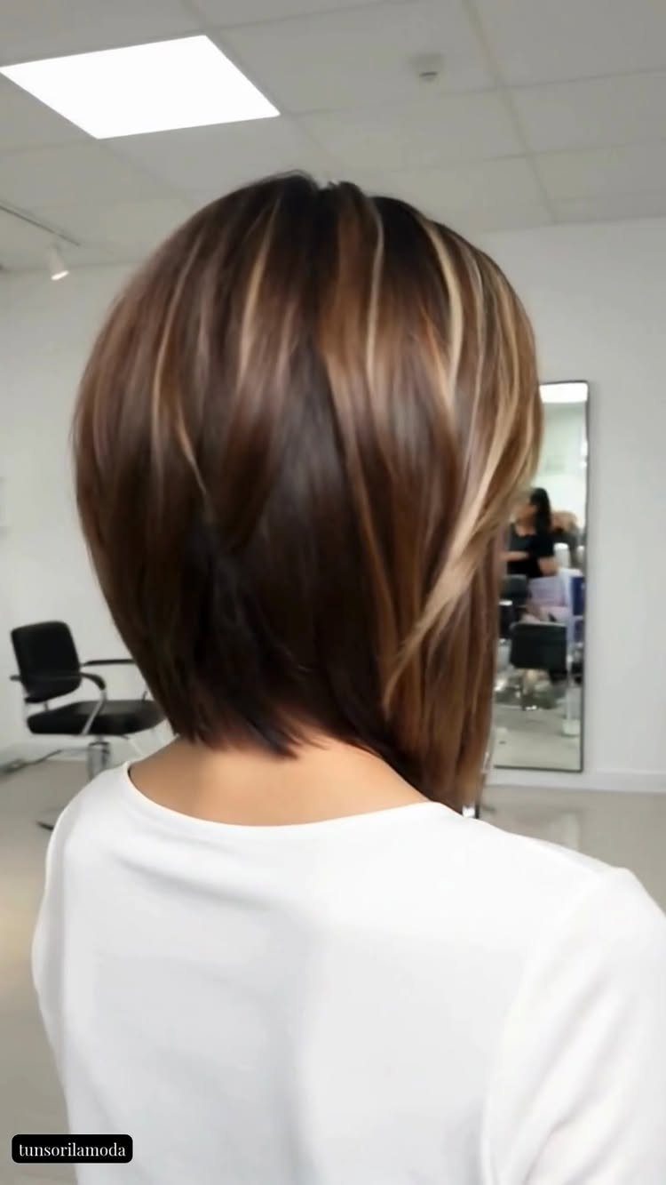 Short layered brown bob with blonde highlights, viewed from behind in a salon
