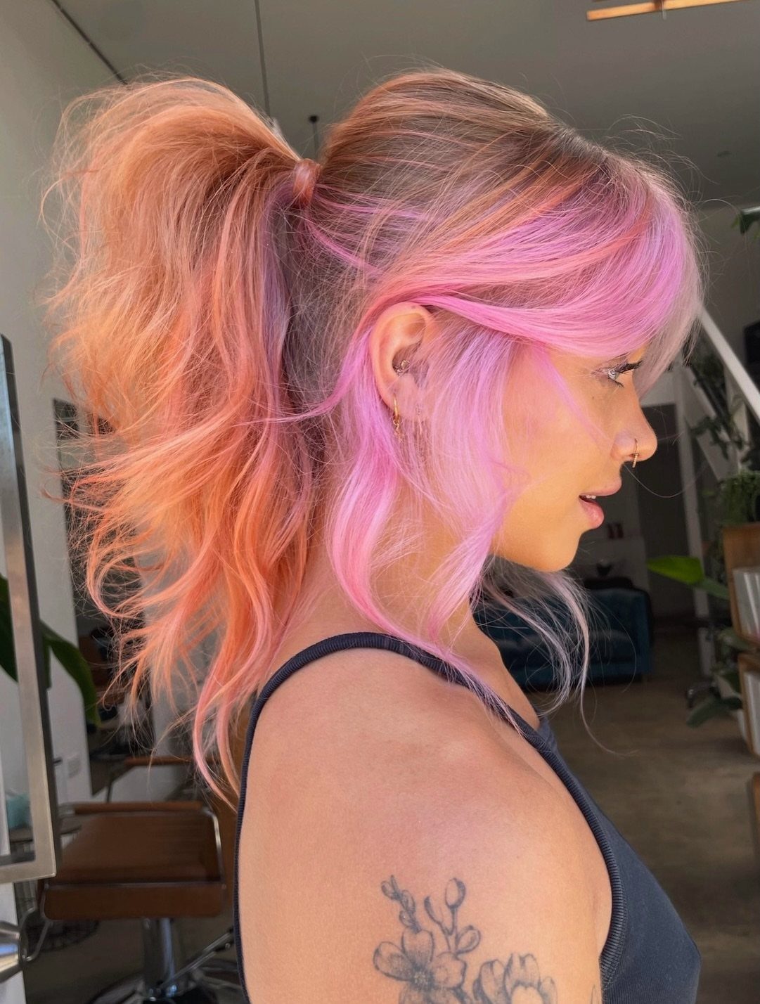 Woman with a high ponytail showing peach-pink hair beneath and behind her ear