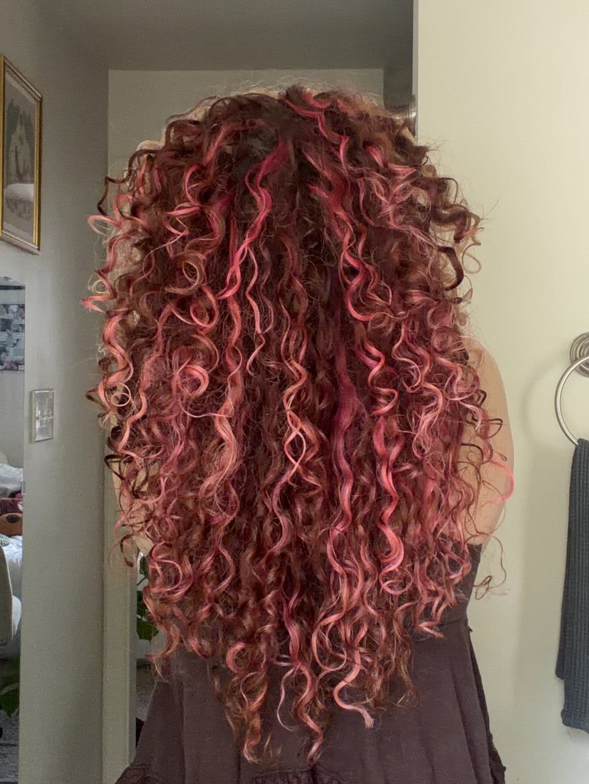 Long brown curls with vivid pink peekaboo strands throughout