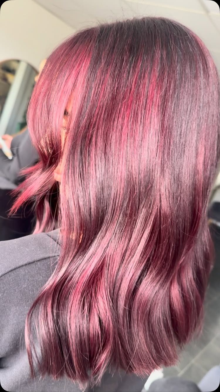 Long wavy hair shows a glossy blend of deep plum and burgundy tones