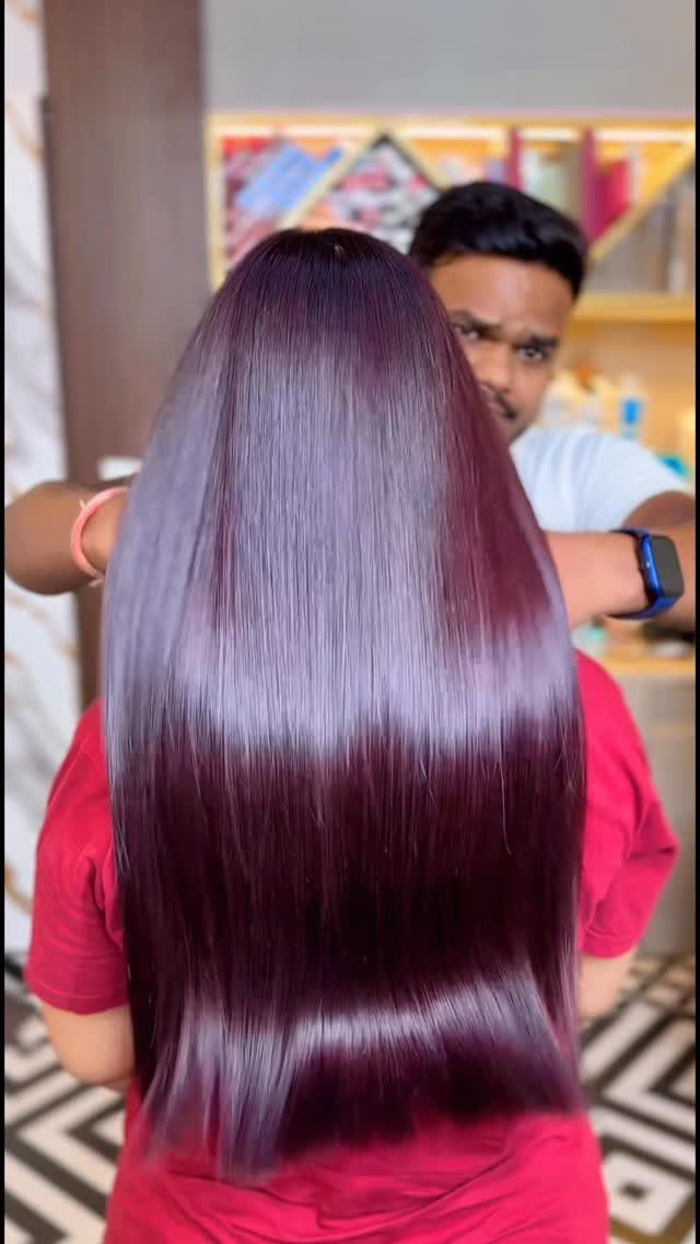 Long, glossy bright plum hair shown from behind in a salon