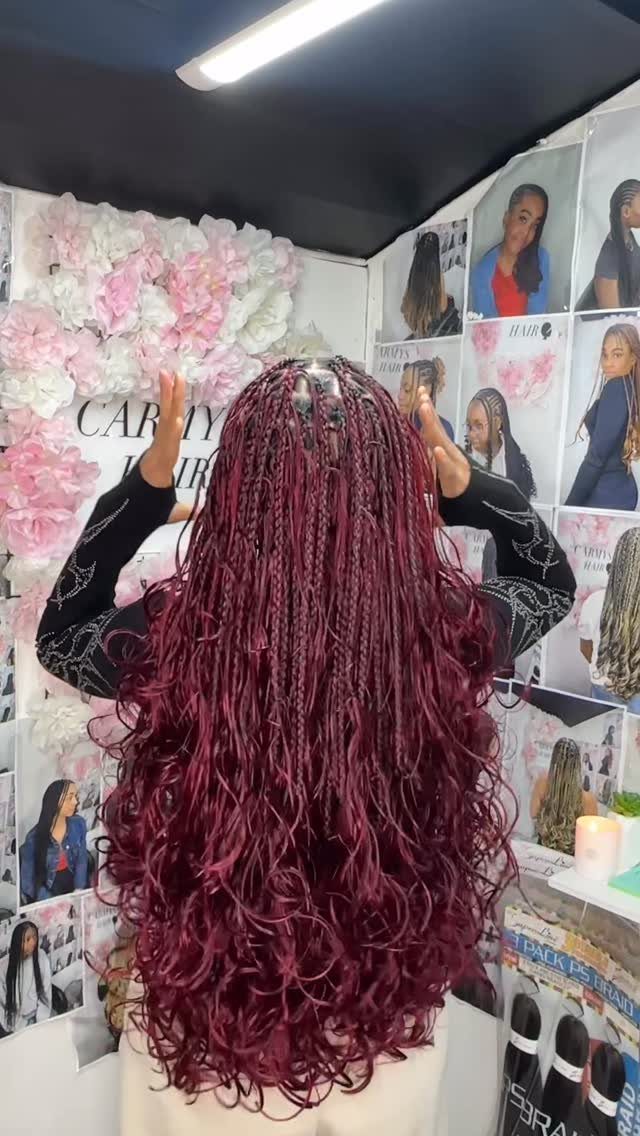 Long plum braids with curled ends displayed from behind in a salon
