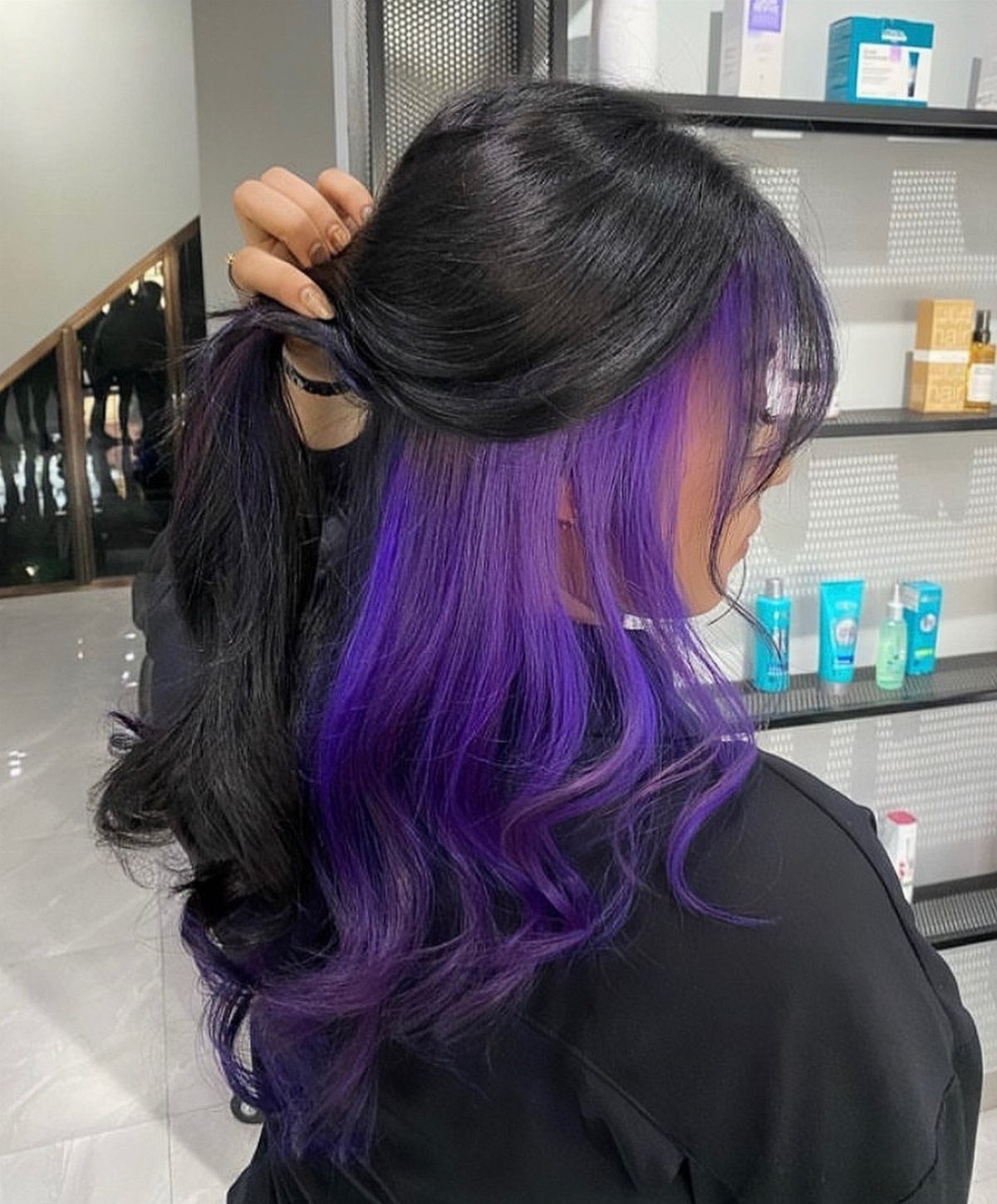 Black-haired person lifts the top layer to reveal vivid plum-purple underlayers