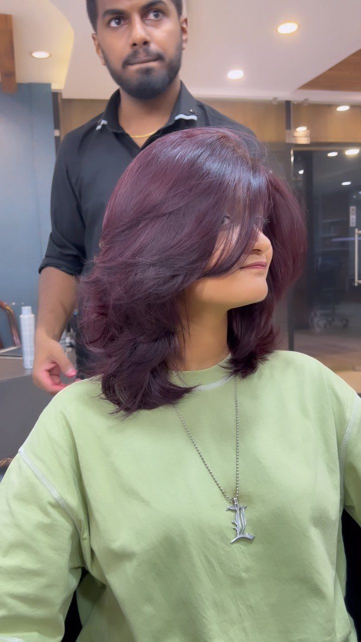 Layered plum hair styled in voluminous waves at a salon