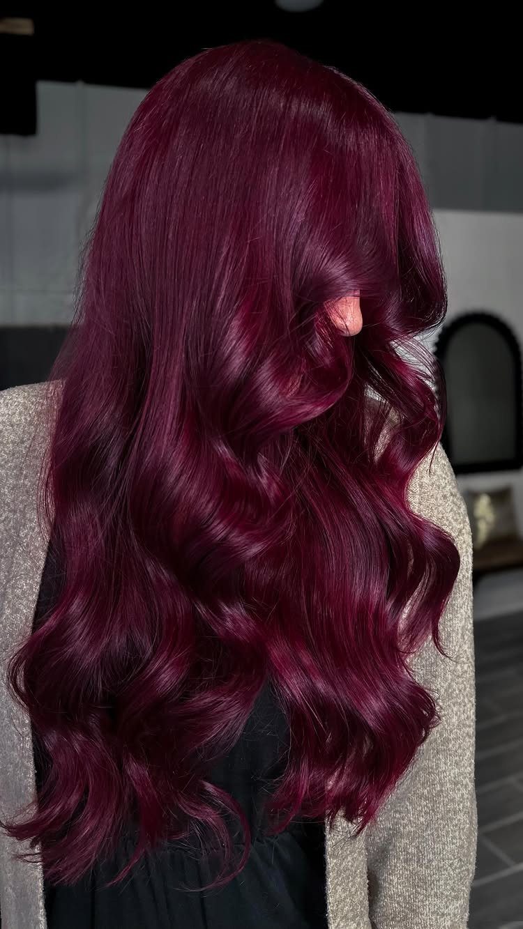 Long raspberry-plum hair falls in glossy, defined waves down the back.