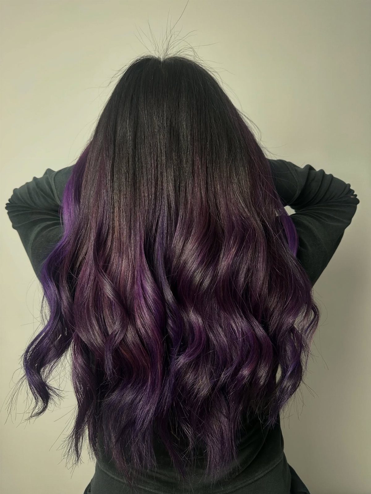 Long wavy hair transitions from dark roots to vivid plum-purple ends