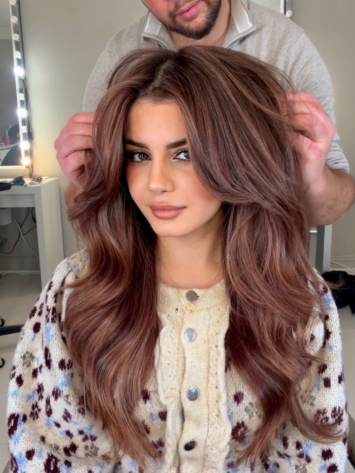 Long brunette waves with rose-gold highlights styled by a salon professional